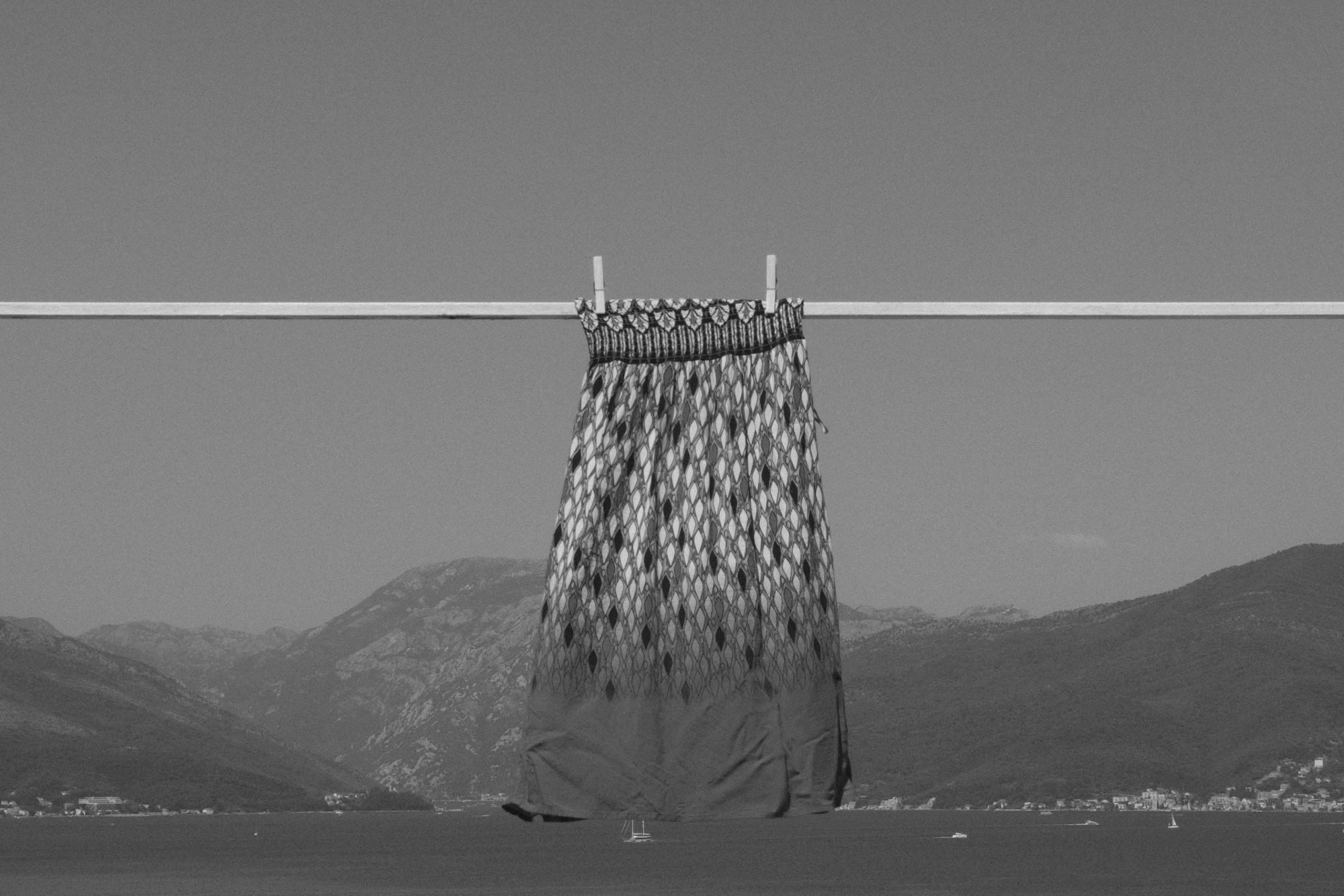 A patterned skirt drying on a rooftop line above a bay